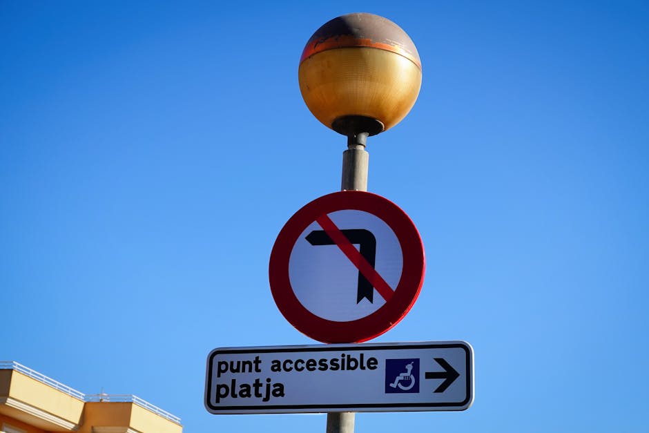 A close-up view of a painted wheelchair-accessible parking space symbol on an asphalt surface, featuring a yellow wheelchair icon and an arrow pointing to the right. The surface shows slight texture a
